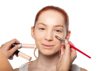 Professional Make-up artist doing glamour with red hair model makeup.  Isolated background. 