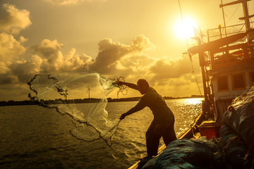 Silhouettes fisherman casting on a crab boat.