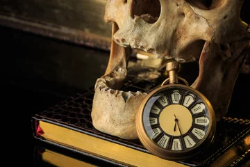 Fotobehang Oude meesters human skull on a book next to the clock. concept of black magic  © kopitinphoto