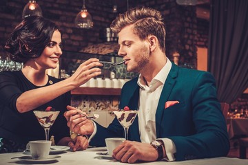 Stylish wealthy couple having desert and coffee together in a restaurant.