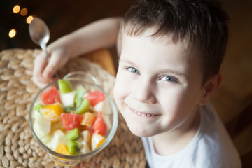 Happy smiling kid holding a large bowl of fruit salad