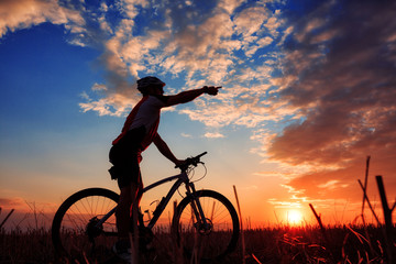 Obraz premium Man Cyclist with bike on sunset
