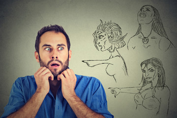 Bad evil women pointing at stressed anxious young man