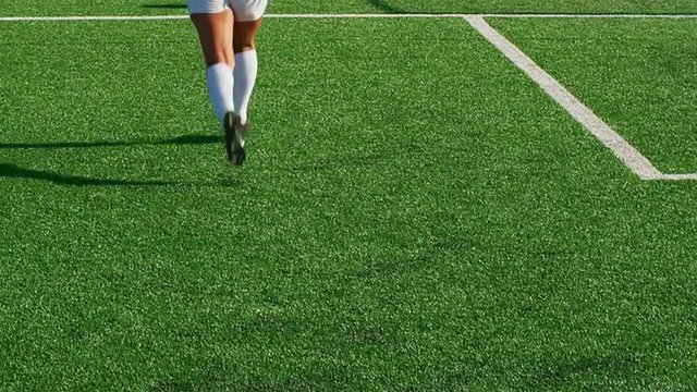A female soccer player slide tackles an opponent during a game