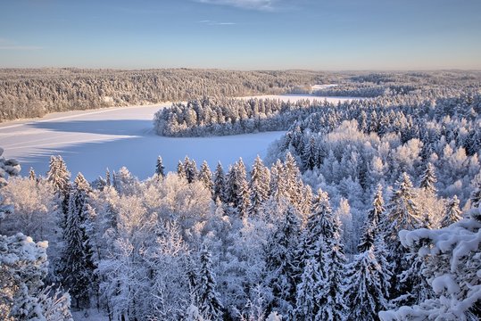 Aerial view of snowy lake and forest at Aulanko nature park in Finland. Late afternoon Sun shining in frozen landscape. HDR image.