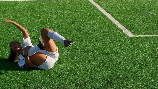 An injured female soccer player motions for the ref to give her opponent a red card