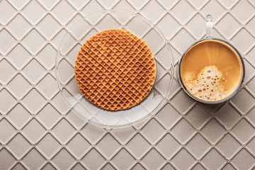 Cup of coffee with wafer on the relief background top view