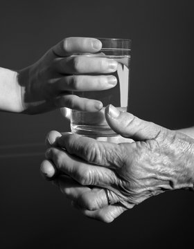 hands of grandmother and grandchild with the glass of water

