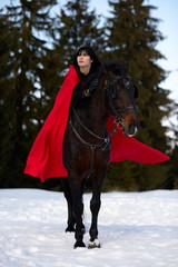 beautiful woman with red cloak with horse outdoor in winter