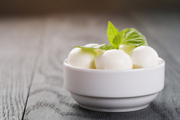 small balls of mozzarella in bowl with basil