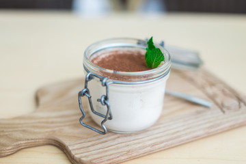 dessert with fruits, nuts and cream cheese in glass jar on wooden background