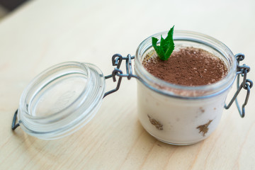 dessert with fruits, nuts and cream cheese in glass jar on wooden background