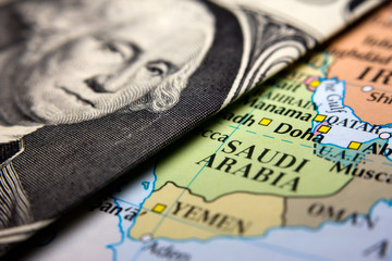 A dollar bill (figuring George Washington) on top of a map of Arabia