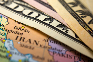 Dollar bills on top of a map showing Iran