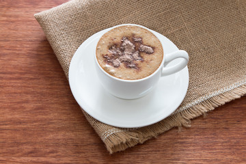 A cup of cappuccino at the wooden table