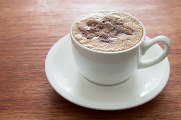 A cup of cappuccino at the wooden table