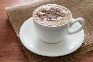 A cup of cappuccino at the wooden table