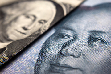 Close-up of an American dollar bill (showing George Washington) and a Chinese yuan banknote (Mao...