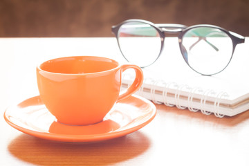 Close up of coffee cup with book and eyeglasses