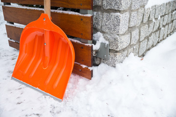 Snow removal. Orange Shovel in snow, ready for snow removal, outdoors.