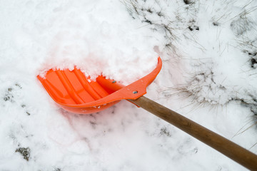 Snow removal. Orange Shovel in snow, ready for snow removal, outdoors.