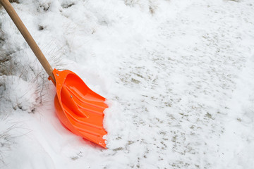 Snow removal. Orange Shovel in snow, ready for snow removal, outdoors.