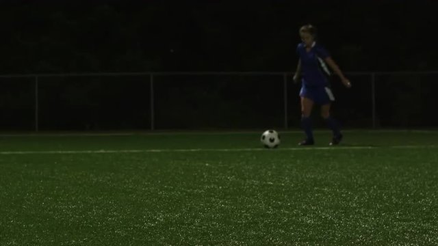 A female soccer player kicks the ball back into play