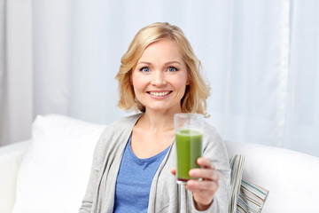 happy woman drinking green juice or shake at home