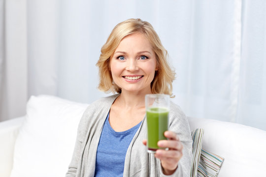 Happy Woman Drinking Green Juice Or Shake At Home