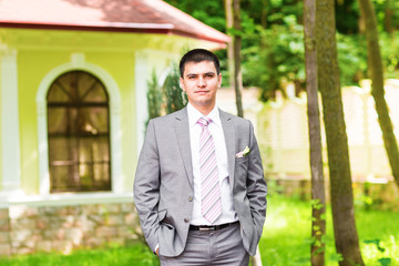 Portrait of the groom in a park on their wedding day.