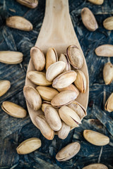 Pistachio Nuts in Wooden Spoon on Blue Background
