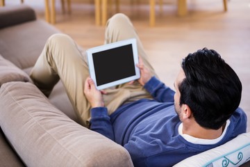 Man using tablet lying on the couch