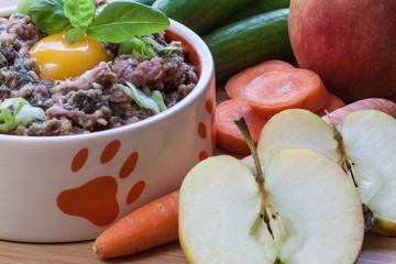 Futternapf mit Barf und Eigelb, dekoriert mit Obst und Gemüse