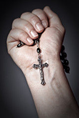 Caucasian hand holds Christian rosary cross wrist. faith, religion