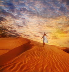 Fototapeta na wymiar Little girl walking down the sand dune