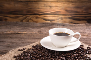 hot coffee and coffee beans on cloth sack top of wooden table
