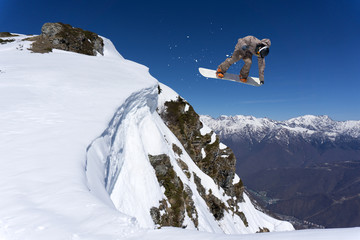 Flying snowboarder on mountains. Extreme sport.