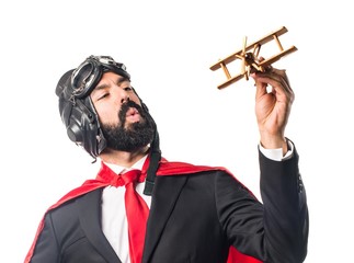 Super hero businessman holding a wooden toy airplane