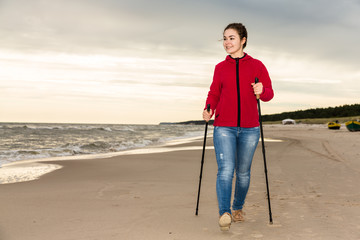 Nordic walking - young woman working out on beach