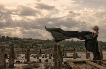 Красивая девушка на фоне контрастного неба с развевающимися волосами. В летящем платье. 