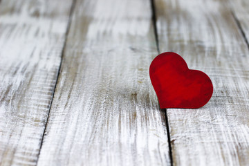 Single red heart on white rustic wood background
