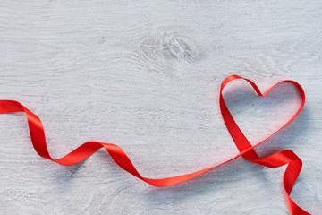 Obraz na płótnie Canvas Red valentines heart shaped ribbon on a wooden background. Valentines Day concept