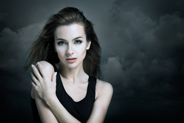 Fototapeta premium Lonely Woman on the Background of Dark Clouds