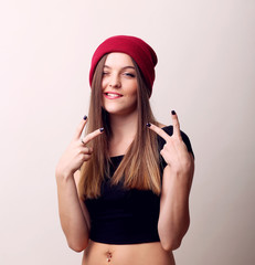 Happy smiling beautiful young woman showing two fingers or victory gesture, isolated over beige background