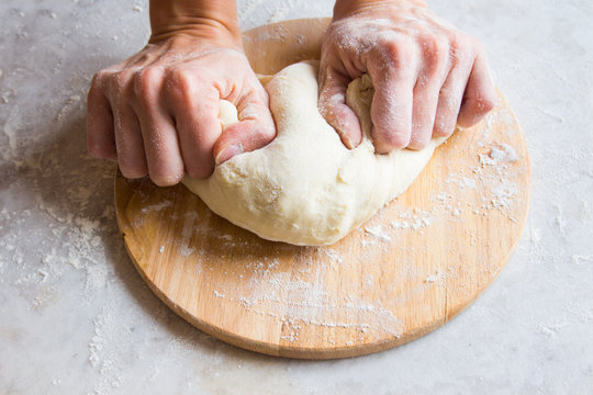 Hands knead dough