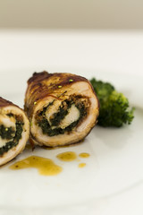 Roulade of turkey with chorizo and spinach. On white plate and white background.