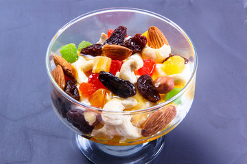 Yogurt with nuts, candied fruits and fruits in a glass.