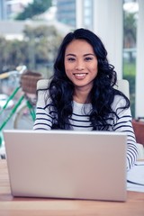 Smiling creative businesswoman using laptop