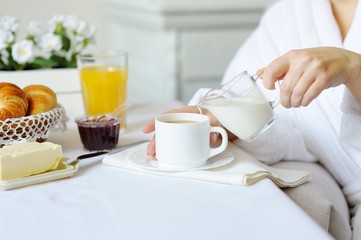 Beautiful woman behind a white table pouring fresh milk.