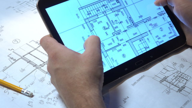 Engineer looking drawings on the tablet.
